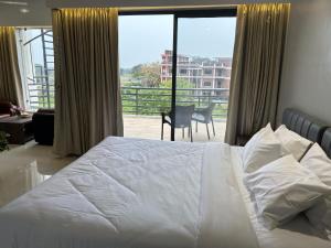 um quarto com uma cama e vista para uma varanda em The Pearl Club Resort em Santiniketan