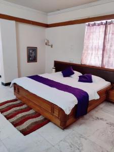 Un dormitorio con una gran cama de madera con almohadas moradas en Hotel Shiva's Regency, en Bikaner
