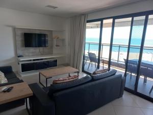 a living room with a couch and a tv and a balcony at Escala Landscape Beira Mar in Fortaleza