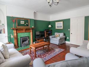 ein Wohnzimmer mit grünen Wänden und einem Kamin in der Unterkunft Victoria House in Alnwick