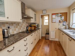 a kitchen with white cabinets and a wooden floor at Victoria House in Alnwick +7 photos