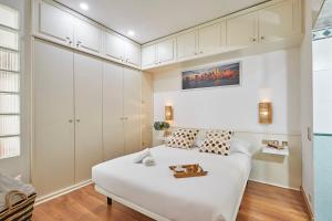 um quarto com uma cama branca e armários brancos em BBarcelona Gràcia Nova Flat em Barcelona