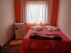 a bedroom with a red bed with a window at Hostel Raio de Fogo in Paraty