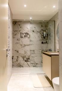 La salle de bains est pourvue d'une douche en marbre, de toilettes et d'un lavabo. dans l'établissement BW Aurora Lux Panorama, à Belgrade
