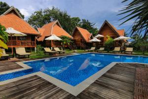 een zwembad van het resort met stoelen en parasols bij Angkor Heart Bungalow in Siem Reap