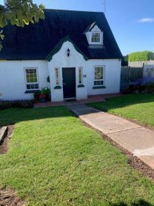 a white house with a black roof and a yard at Bayview, Dunmore East, County Waterford - Sleeps 12 persons in Dunmore East