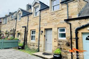 una vecchia casa di mattoni con una porta bianca di 2Fountains Cottage - Hadrian's Wall a Greenhead