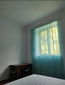 a bedroom with a bed and a window with blue curtains at MG Guest House in Ijevan