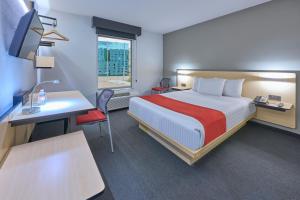 um quarto de hotel com uma cama e uma secretária com um computador em City Express by Marriott Toluca em Toluca