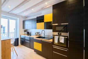una cocina con armarios negros y amarillos y fregadero en LE BLUM COEUR - Hyper Centre Nantes, en Nantes