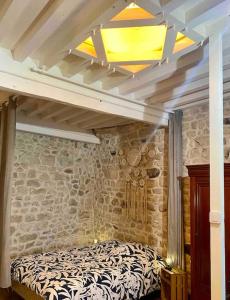 Bett in einem Zimmer mit einer Steinmauer in der Unterkunft Le nid du coq d'or location appartement 