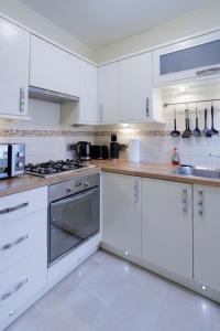 a white kitchen with white cabinets and appliances at Luxury Apartment in Kensal Rise in London