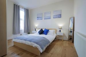 a white bedroom with a large bed with blue pillows at Luxury Apartment in Kensal Rise in London
