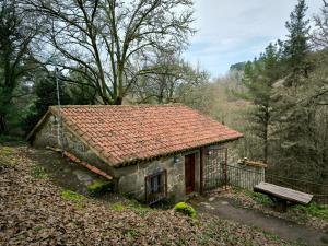 uma pequena casa de pedra com um banco ao lado em Casa Bodega Sacra em Pereiro de Aguiar