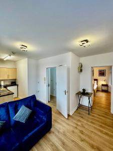 a living room with a blue couch and a kitchen at Rooms Near Me - Apartment 4 Netflix Fast Wifi in Quinton