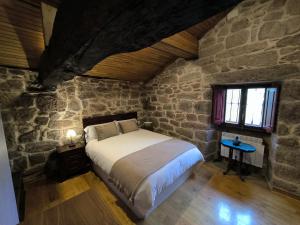 um quarto com uma cama numa parede de pedra em Casa Bodega Sacra em Pereiro de Aguiar