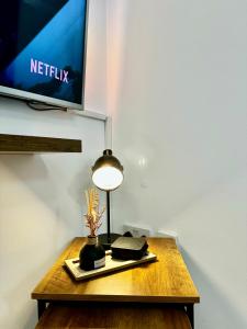 a table with a lamp and a tv on a wall at Rooms Near Me - Apartment 4 Netflix Fast Wifi in Quinton