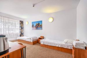 a bedroom with two beds and a table and a tv at Hotel Biała Gwiazda in Kraków