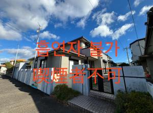 una casa con escritura roja en un lado de ella en ゲストハウス宮崎 guesthouse miyazaki バックパッカー向け個室旅人宿 P有, en Miyazaki