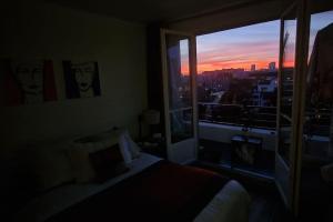 a bedroom with a window with a view of a city at Appartement cosy avec balcon et vue dégagée in Montreuil