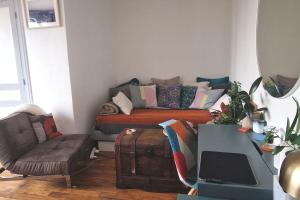 uma sala de estar com um sofá com almofadas em Appartement cosy avec balcon et vue dégagée em Montreuil