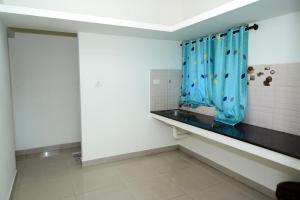 baño con cortina de ducha azul y ventana en Hotel Aradhya Inn Deralakatte, en Mangalore