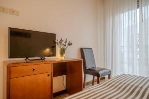 una camera da letto con scrivania, TV e sedia di Hotel Mia a Rimini