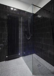 Baño de azulejos negros con ducha y puerta de cristal en whiterooms collection, en Cesena