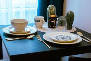 a table with plates and cups and utensils on it at Lima Mini - cozy apartment - in Győr