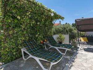 two lounge chairs sitting on a patio next to a hedge at Apartments Loredana in Poreč