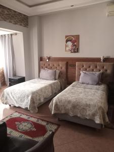 a bedroom with two beds and a rug at Hotel Darna in Rabat