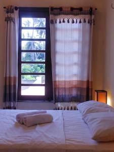 a bed with two towels on it in front of a window at Pousada Viva Praia in Paracuru