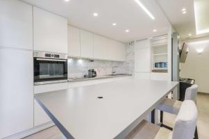 a white kitchen with a large white counter top at Beautiful Apartment Near Parc de la Villette in Paris