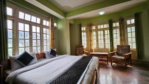 - une chambre avec un grand lit et quelques fenêtres dans l'établissement Ecotel kalimpong, à Kalimpong