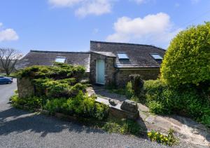a brick house with a white door and some bushes at Corn Loft in Solva