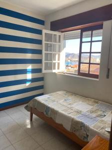 1 dormitorio con cama y paredes de rayas azules y blancas en Vivenda com pátio, no coração do Mindelo, en Mindelo
