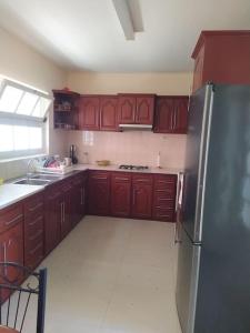 a kitchen with wooden cabinets and a stainless steel refrigerator at Vivenda com pátio, no coração do Mindelo in Mindelo