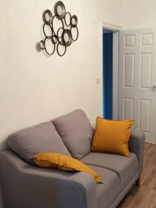a gray couch with yellow pillows in a living room at *Feel at home* 3bed 2bath house Cleethorpes in Grimsby