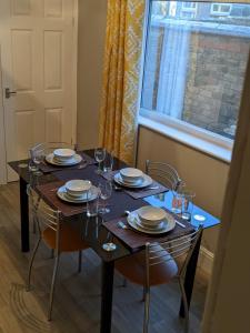 a dining room table with plates and glasses and a window at *Feel at home* 3bed 2bath house Cleethorpes in Grimsby
