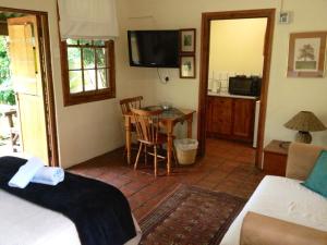 a bedroom with a bed and a table and a television at Figtree Lane Lodge in Richards Bay