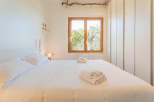 una camera da letto con un grande letto bianco con asciugamani sopra di Affittacamere Incanto nel Verde by Wonderful Italy a Polignano a Mare Altre 63 foto