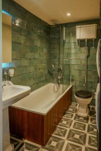 a bathroom with a tub and a toilet and a sink at The White Horse Hotel in Leiston