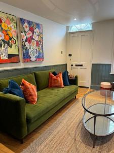 a living room with a green couch and a glass table at Spring Crescent Cottage in Rye in Rye