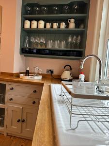 a kitchen with a sink and a shelf with dishes at Spring Crescent Cottage in Rye in Rye