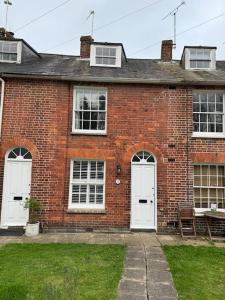 a brick house with two white doors and a bench at Spring Crescent Cottage in Rye in Rye