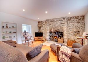 a living room with a stone wall with a fireplace at Crown Cottage in Dolgellau