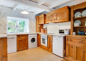a kitchen with wooden cabinets and a washer and dryer at Crown Cottage in Dolgellau