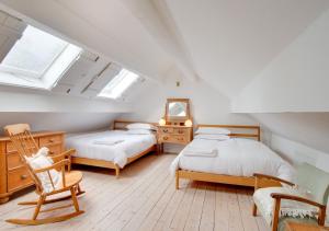 un dormitorio en el ático con 2 camas y una silla en Crown Cottage, en Dolgellau