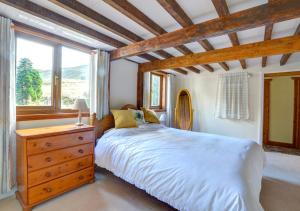 a bedroom with a large bed with a dresser and a window at Tynddol Isaf in Pentre-briwnant