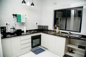 a kitchen with white cabinets and a black counter top at Modern Village Apartments in Chipata